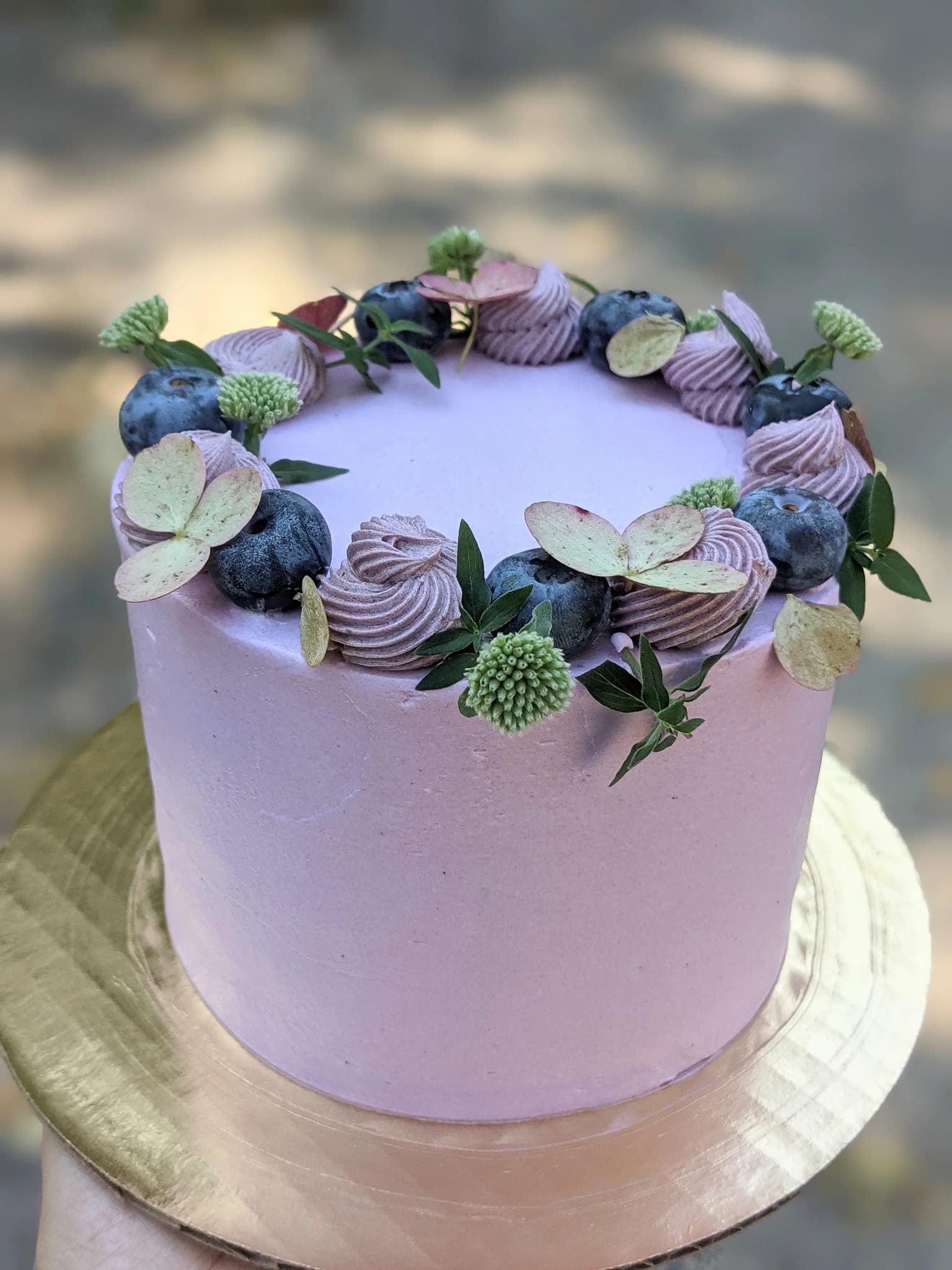 A woman in a white dress is holding a bouquet of blue and white flowers.