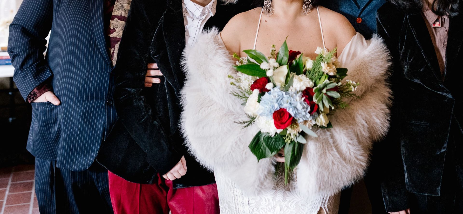 The bride is wearing a fur shawl and holding a bouquet of flowers.