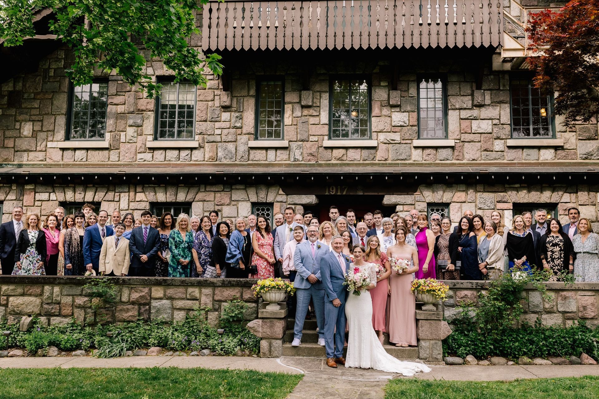 A large group of people are posing for a picture in front of a large stone building.