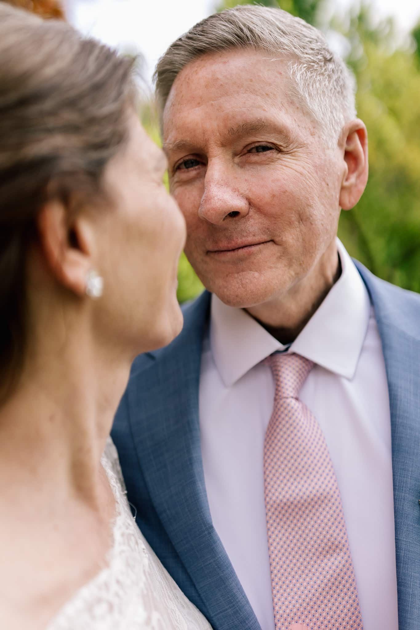 A man in a suit and tie is kissing a woman on the cheek.