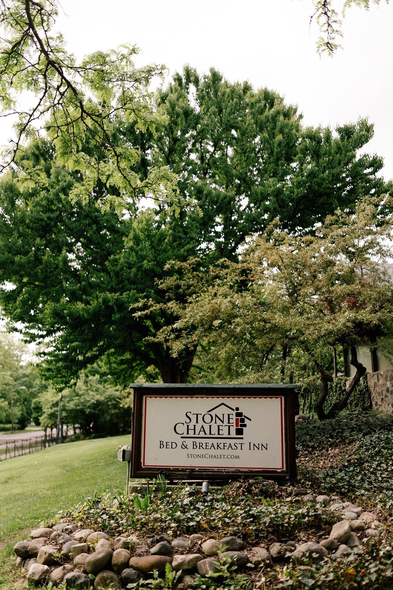 A sign is sitting in front of a tree in a park.