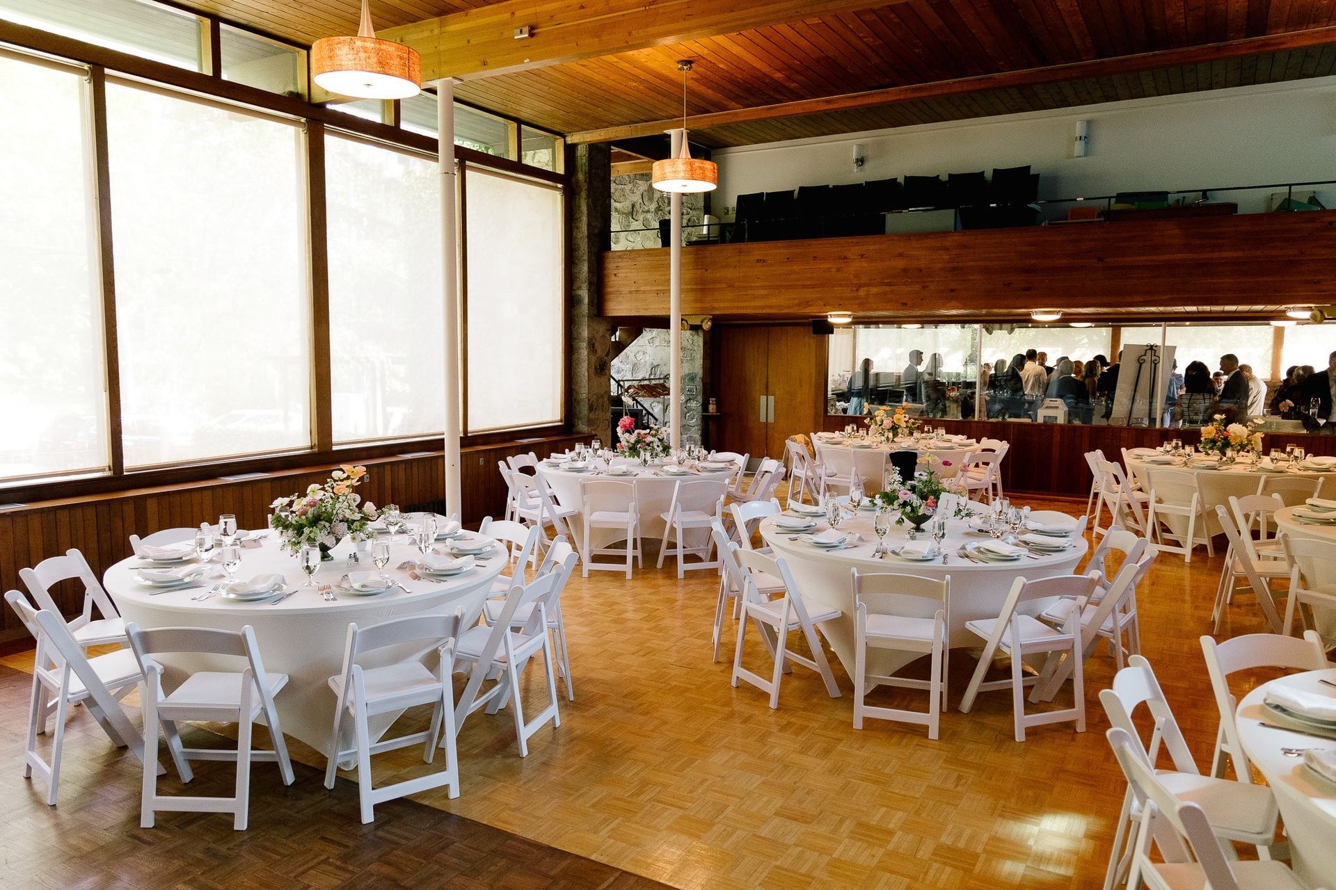 A large room with tables and chairs set up for a wedding reception