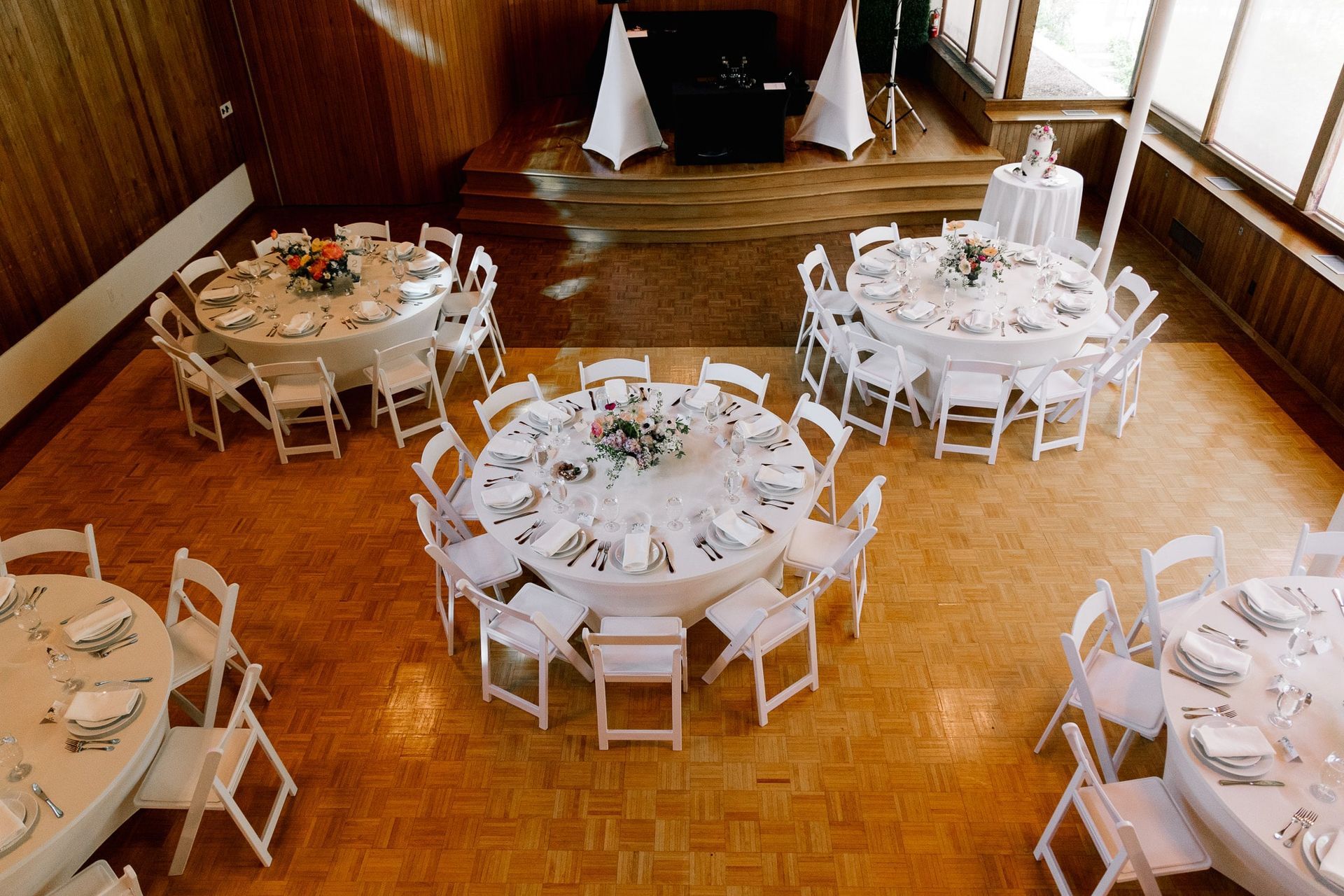A large room with tables and chairs set up for a wedding reception.