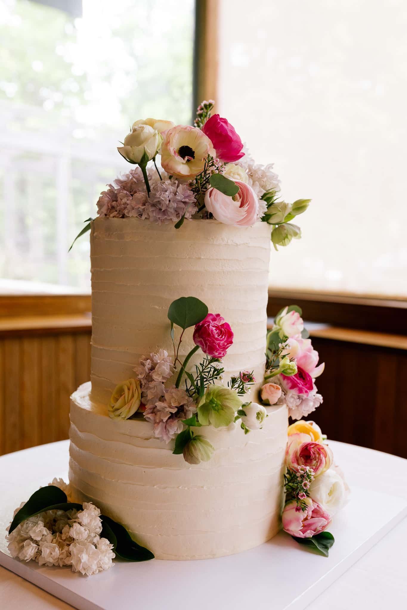 A wedding cake with flowers on top of it is sitting on a table.