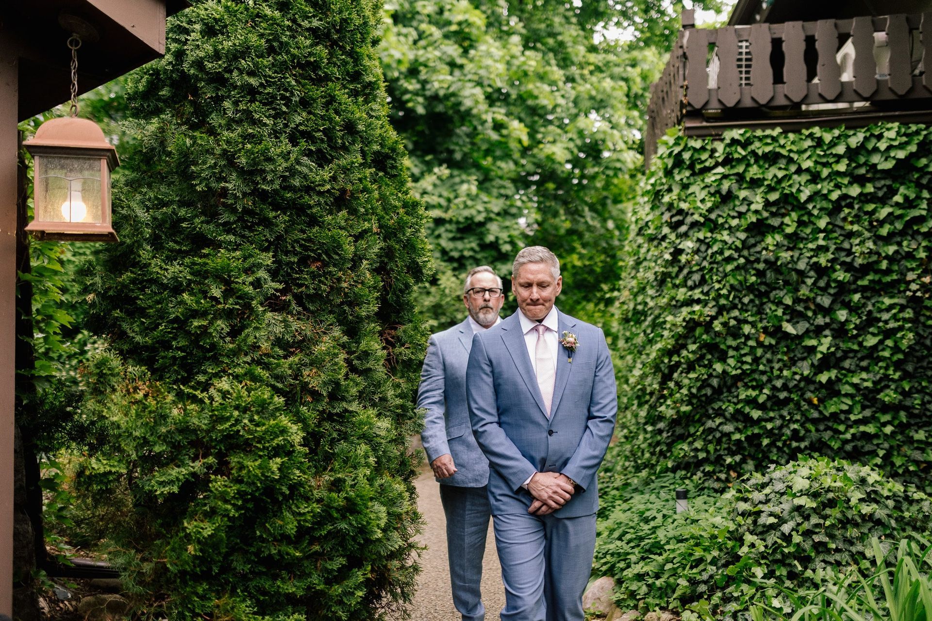 Two men in suits are walking down a path in front of a house.