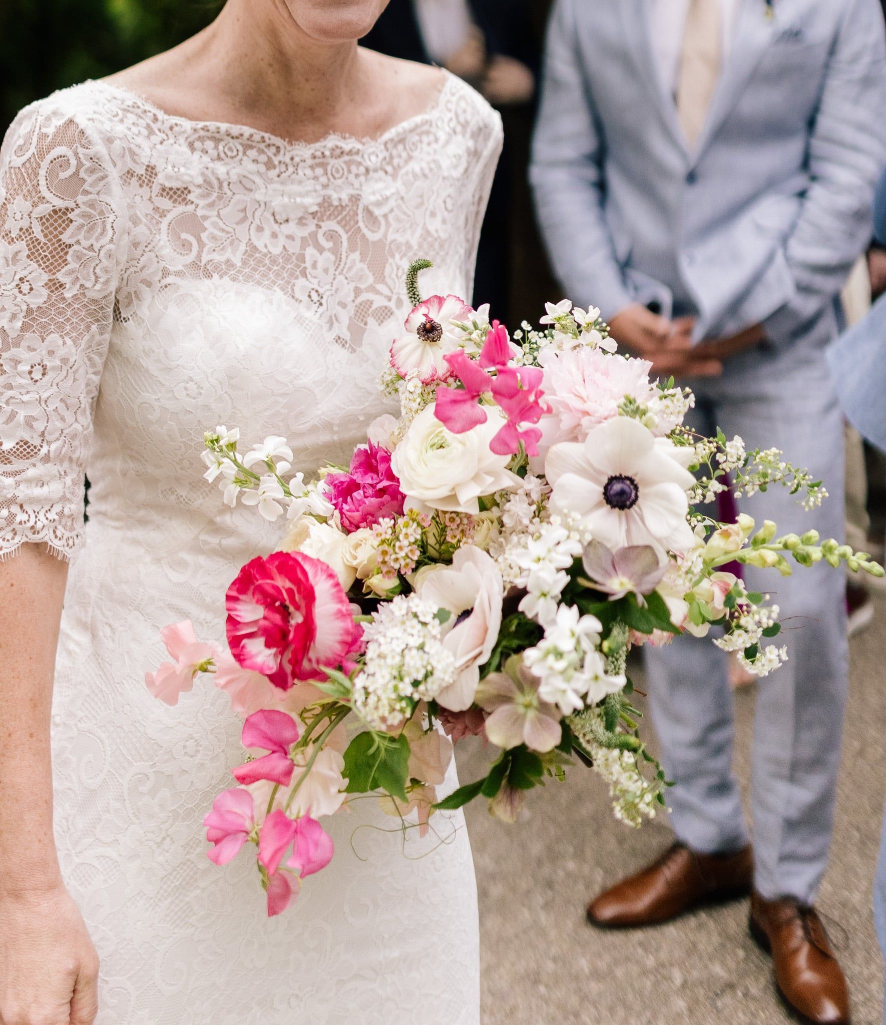 A woman in a white dress is holding a bouquet of pink and white flowers