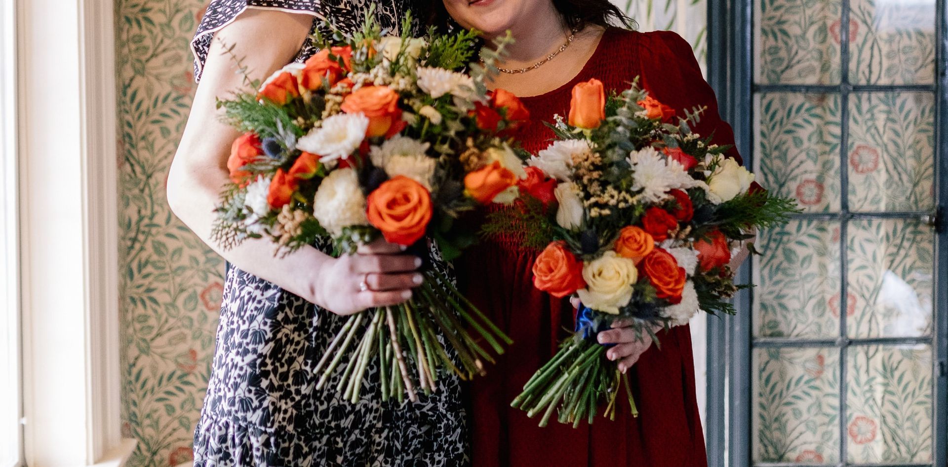 Two women are standing next to each other holding bouquets of flowers.