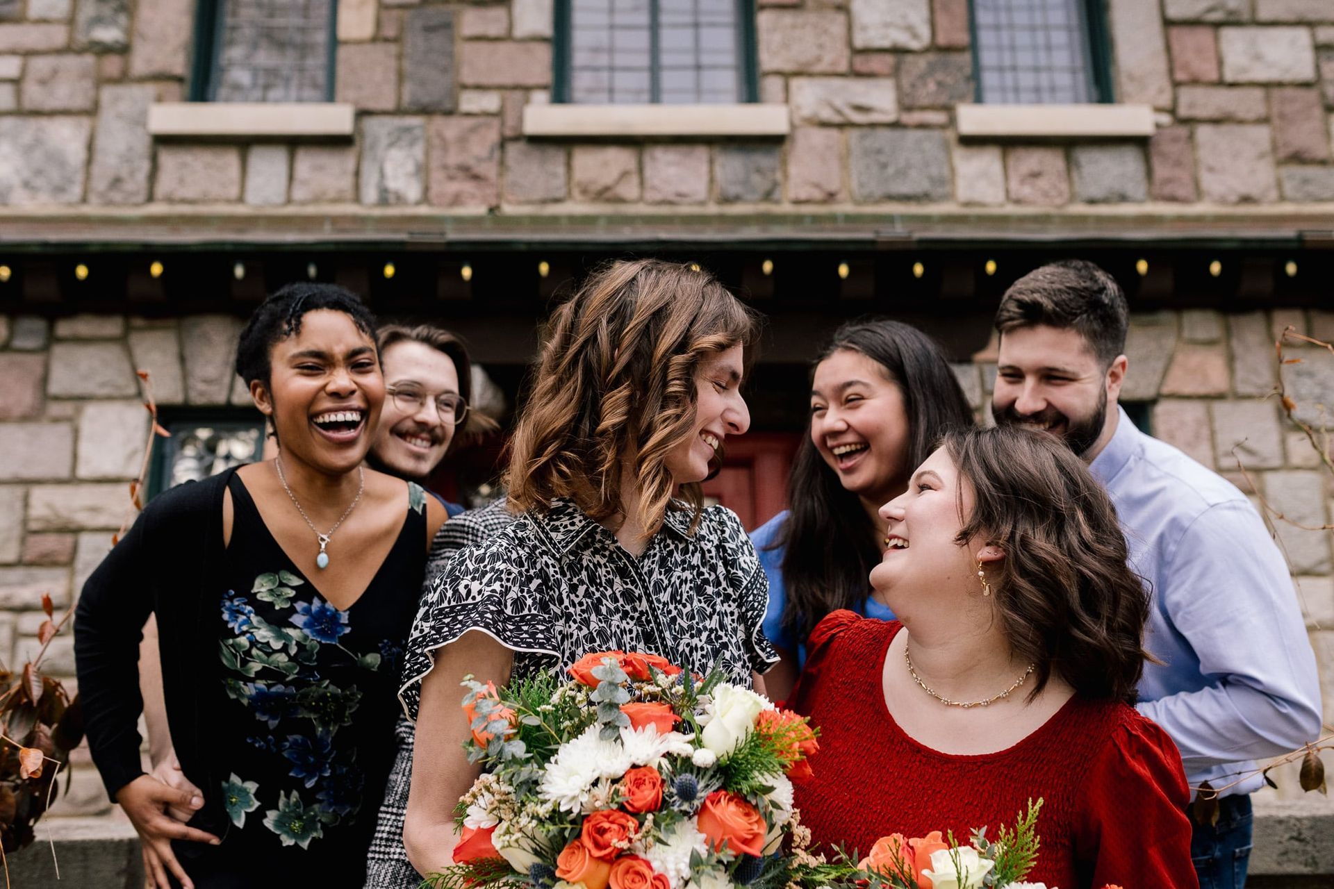 A group of people are standing around a woman holding a bouquet of flowers.