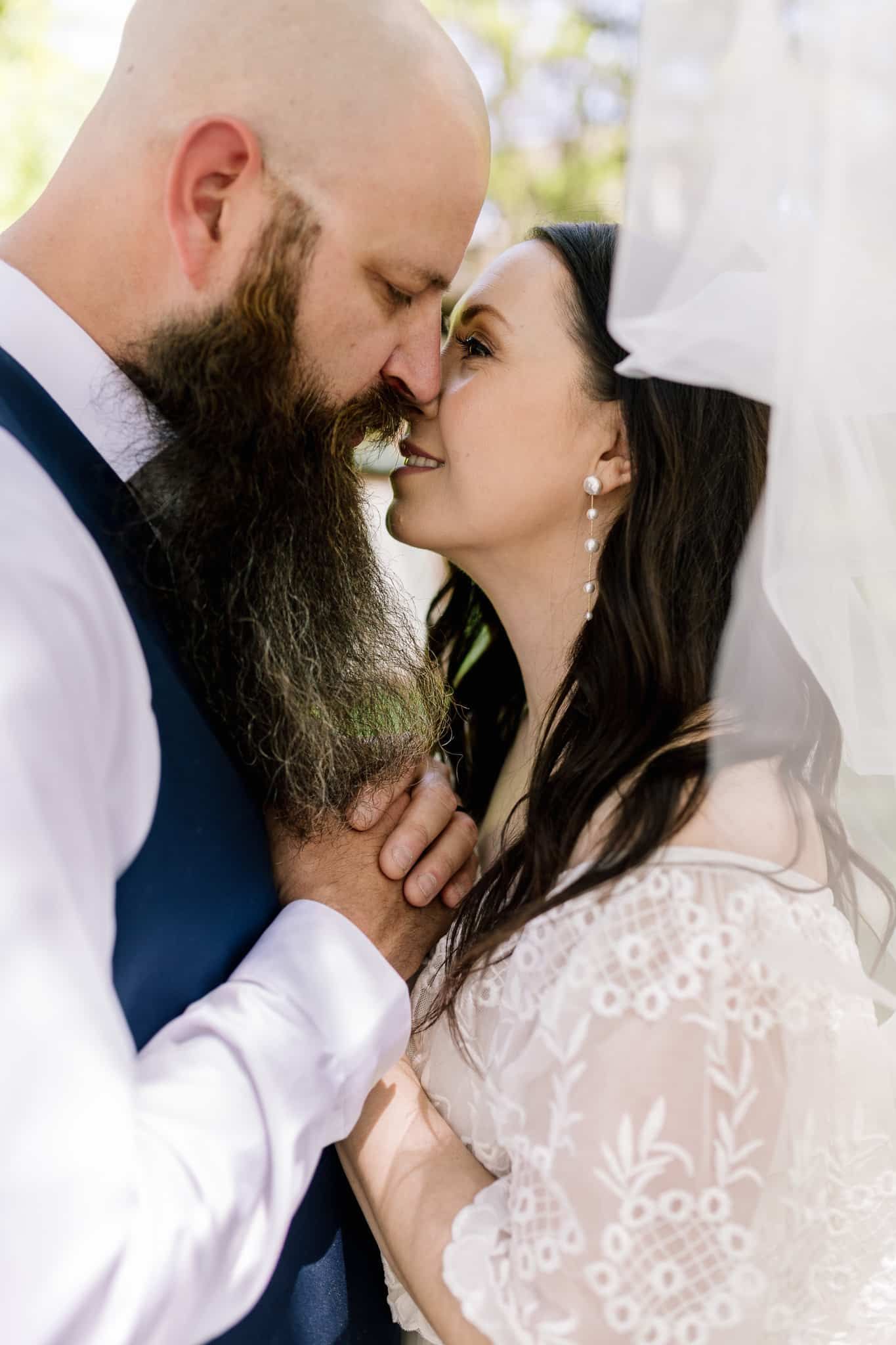 A man with a beard is kissing a woman on the forehead.