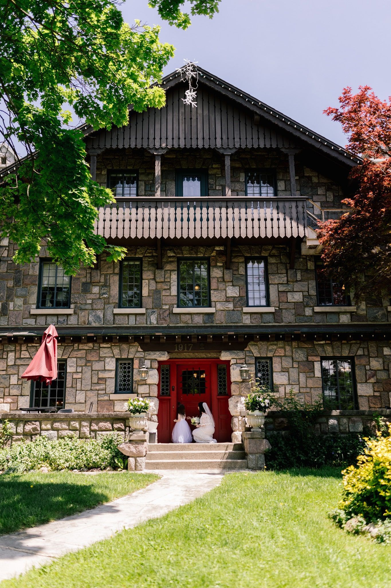 A large stone house with a red door and a balcony