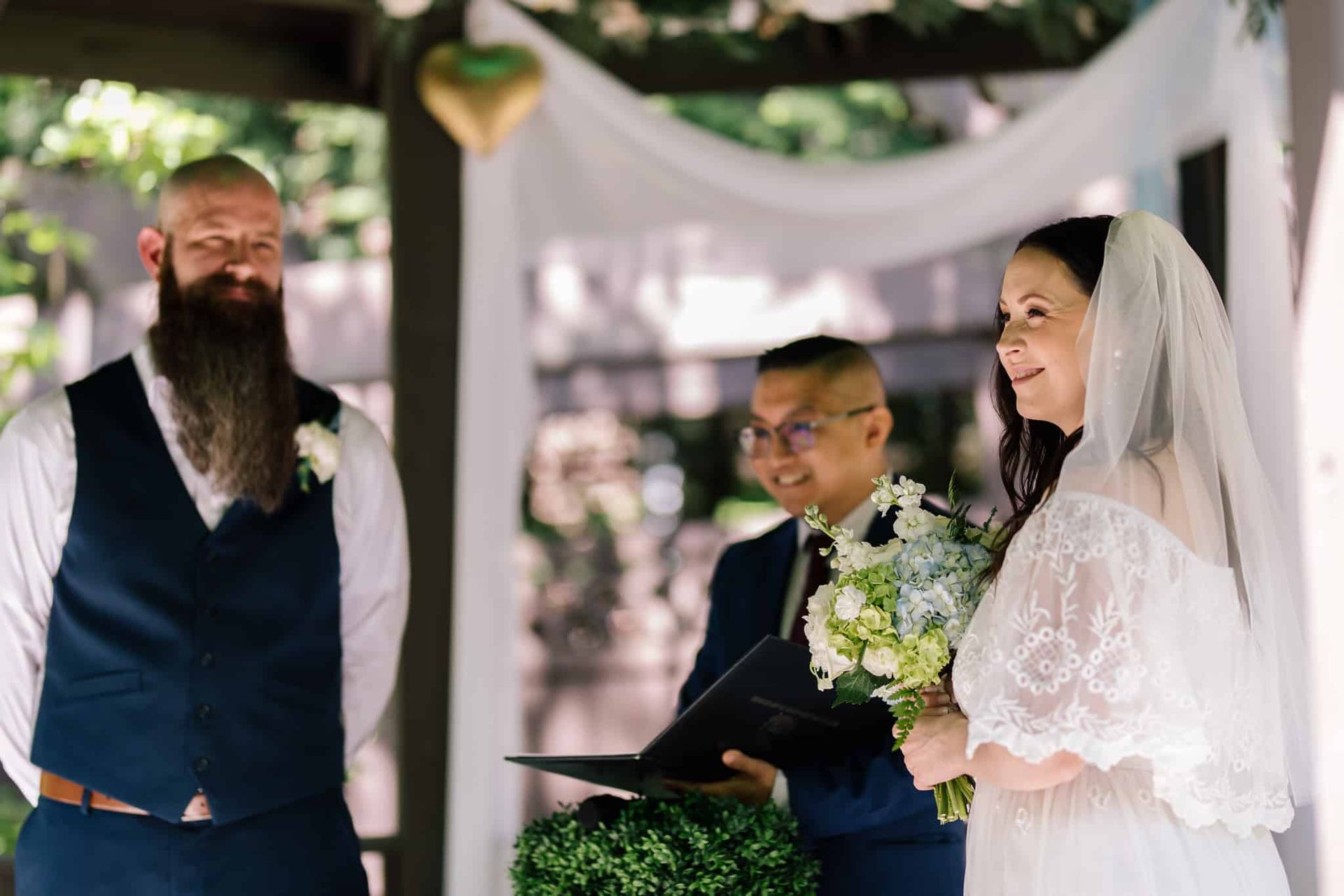 A bride and groom are standing under a canopy during their wedding ceremony.