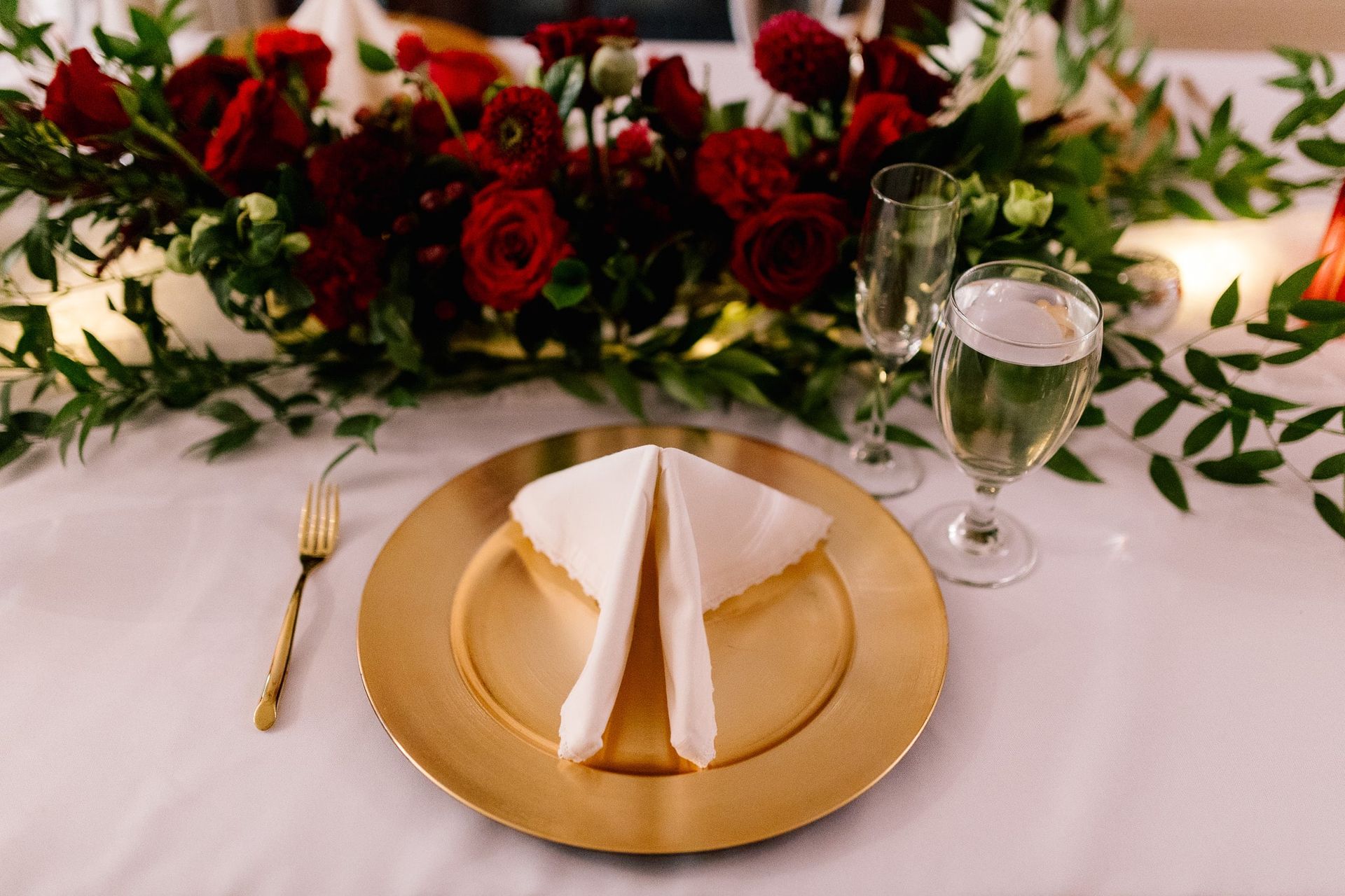 A gold plate with a napkin on it is on a table.