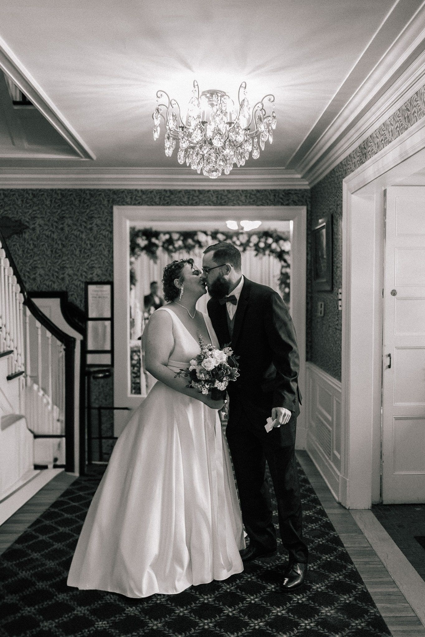 A bride and groom are kissing in a hallway.