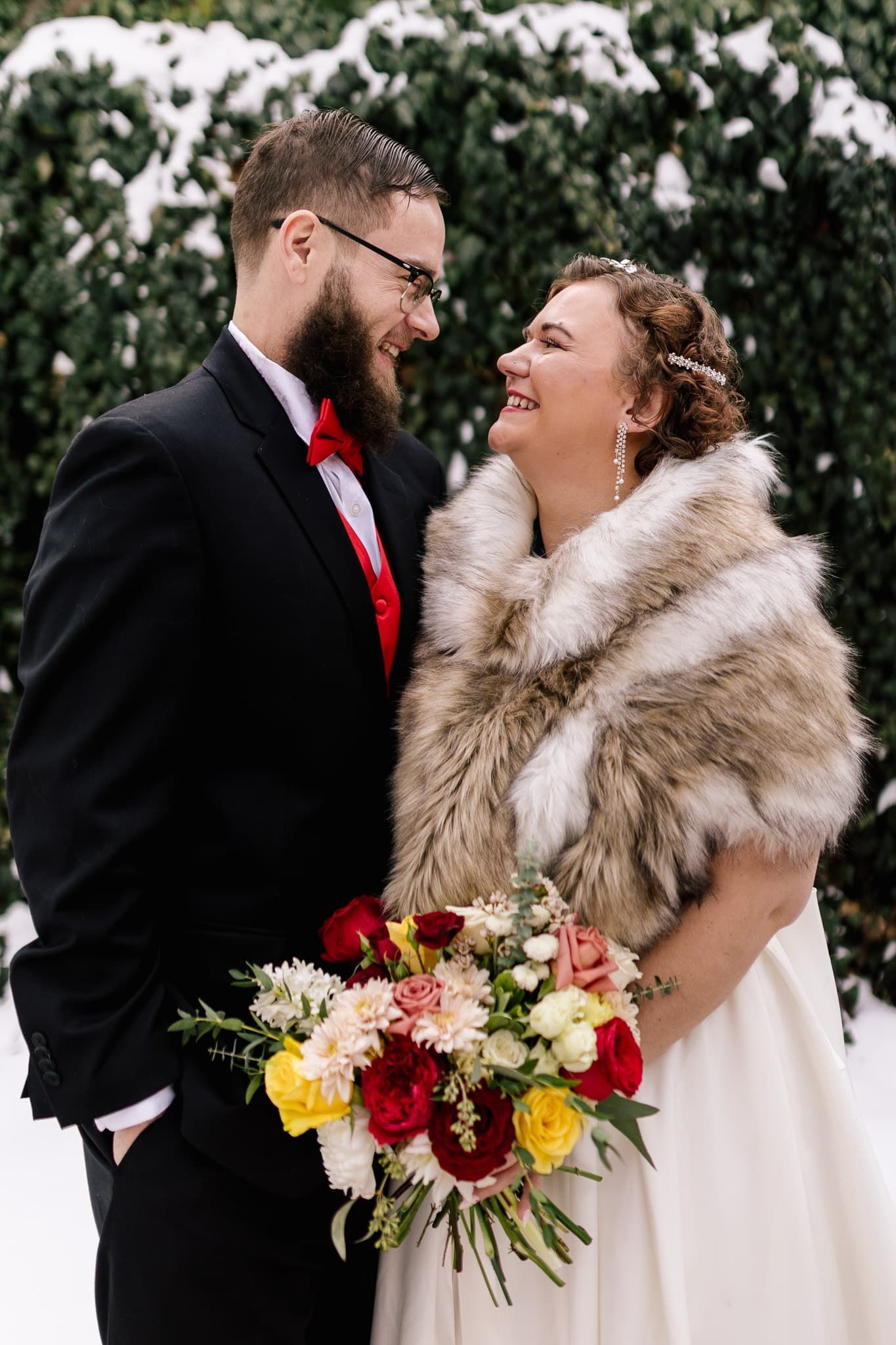 A bride and groom are standing next to each other in the snow.