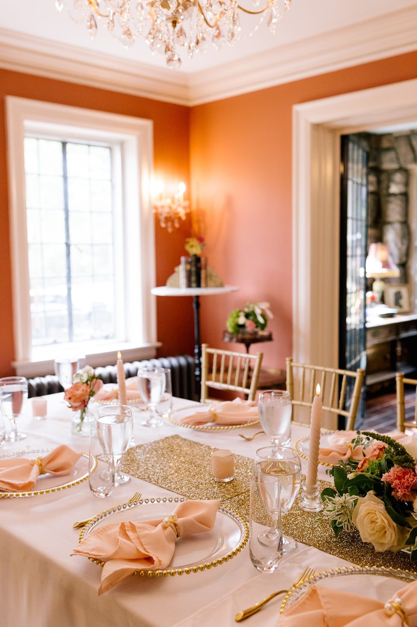 A long table is set for a wedding reception in a room with a chandelier.