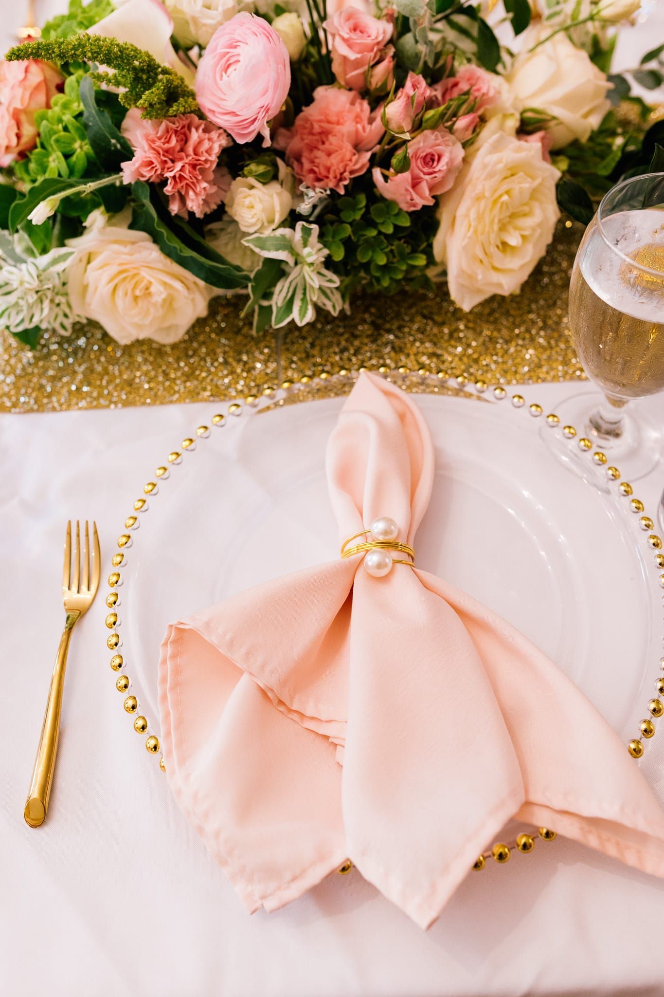 A table setting with a napkin , fork , wine glass and flowers.