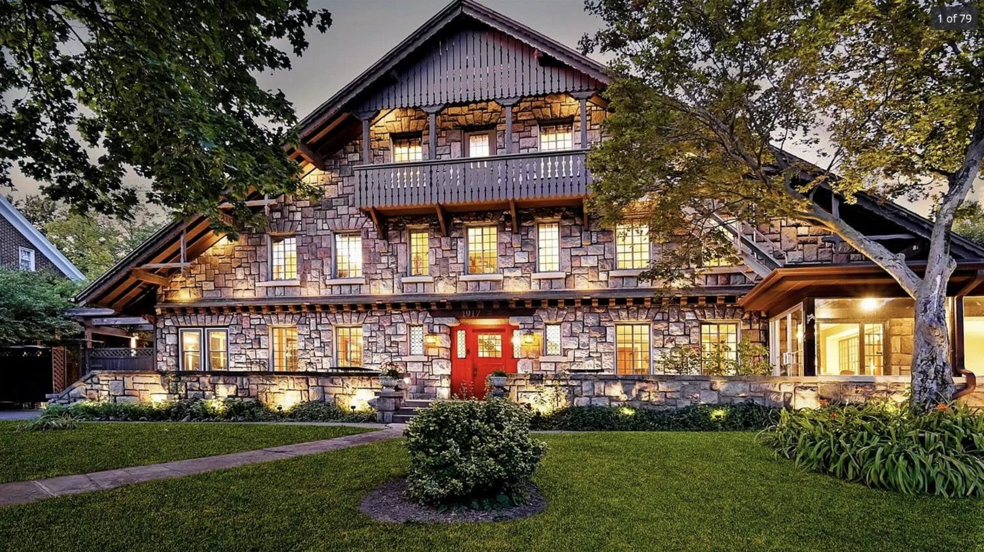 A large stone house with a red door is lit up at night