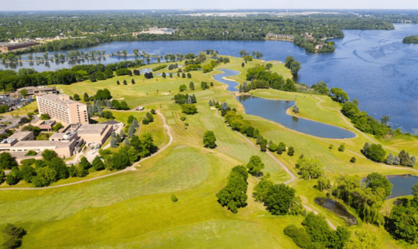 An aerial view of a golf course with a lake in the background.