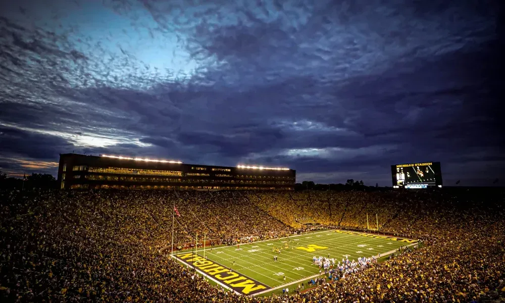 A football stadium filled with people watching a game at night.