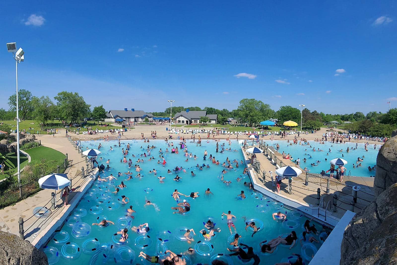 A large swimming pool filled with people on a sunny day.