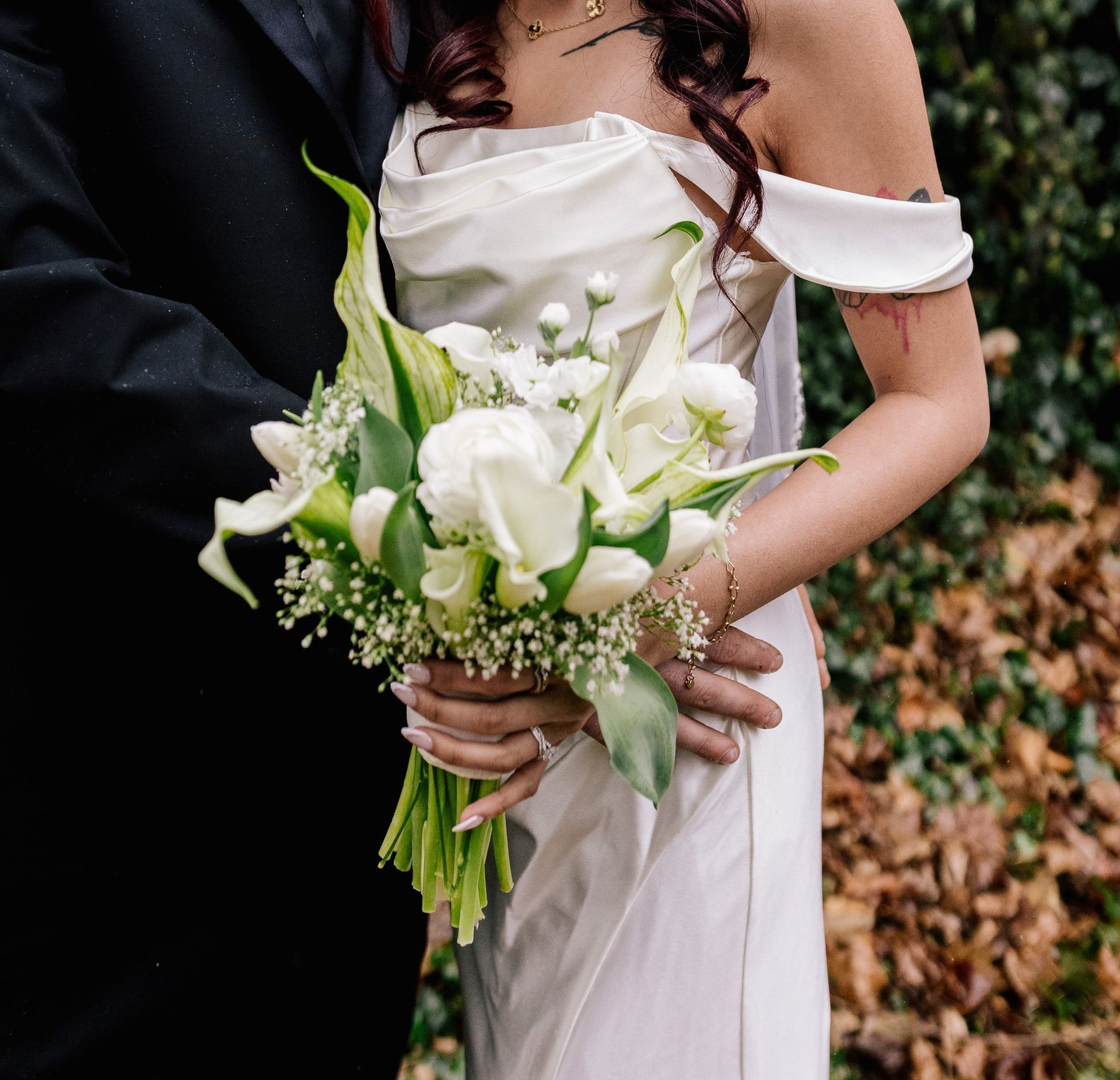 A bride in a white dress is holding a bouquet of white flowers