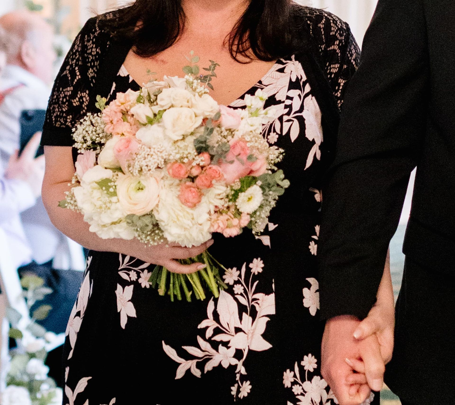 A woman in a black dress is holding a bouquet of flowers