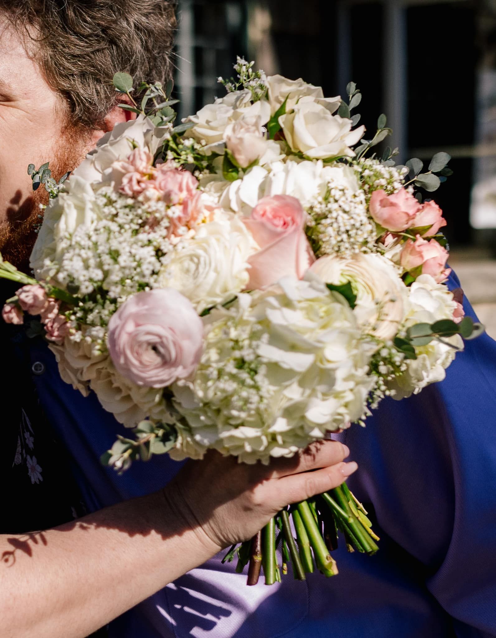 A man is kissing a woman who is holding a bouquet of flowers.