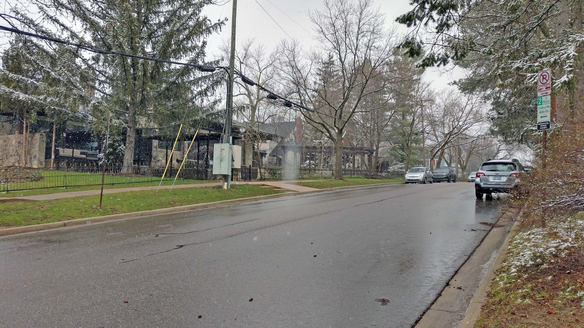 A street with cars parked on the side of it on a rainy day.