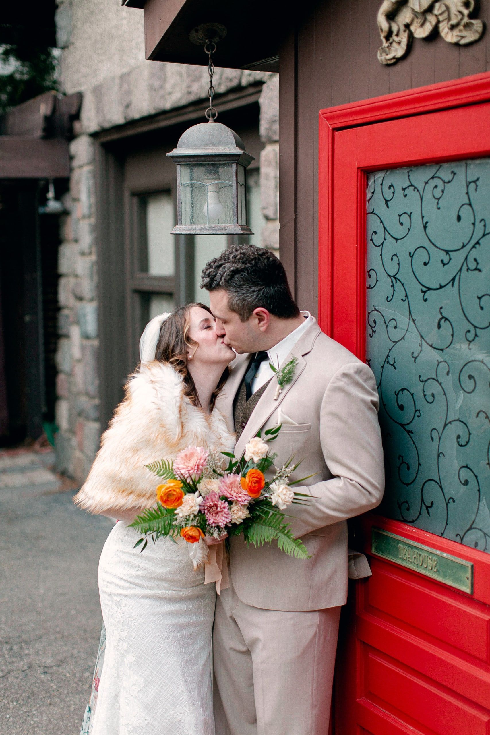 A bride and groom kissing in front of a red door.