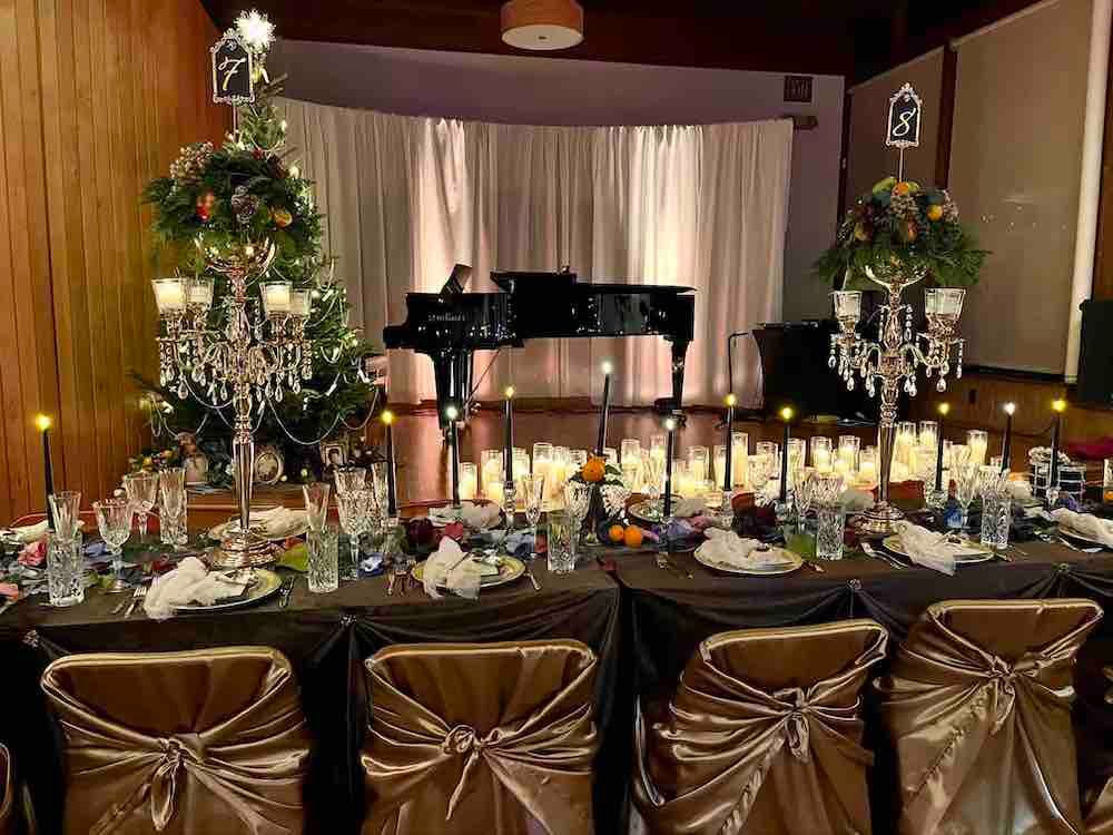 A long table with a piano and a christmas tree in the background.