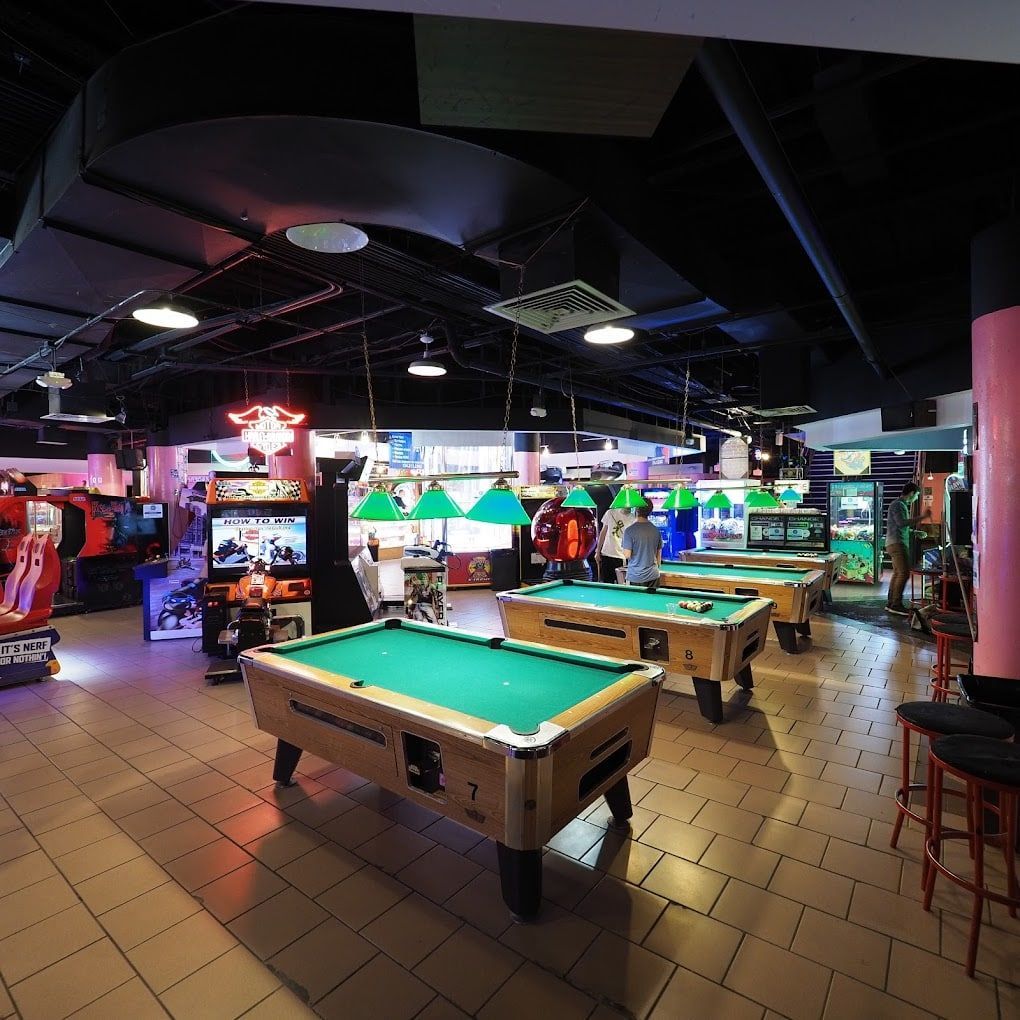 A pool hall with a lot of pool tables and arcade games