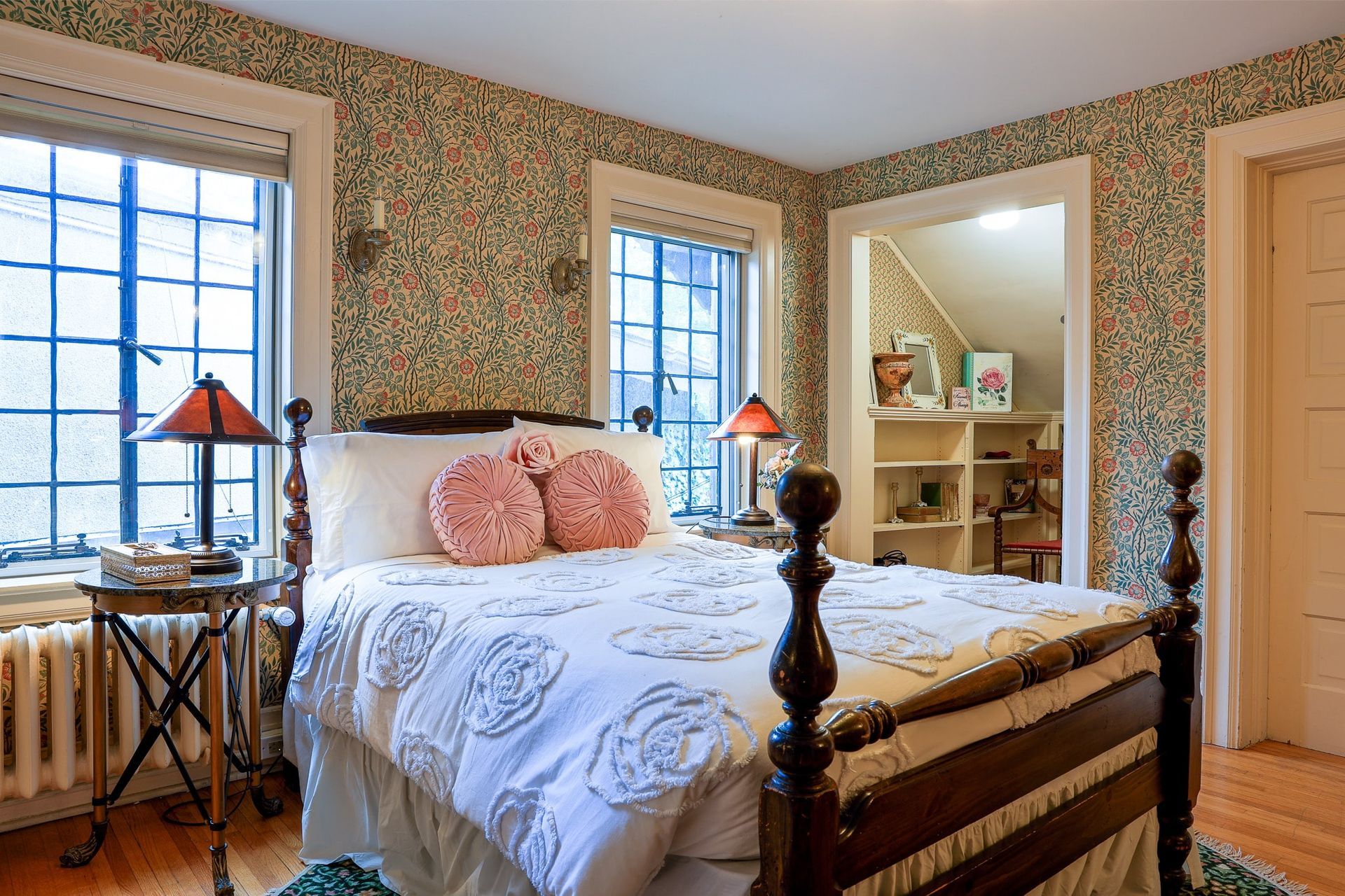 A bedroom with a bed , two lamps , and a window.