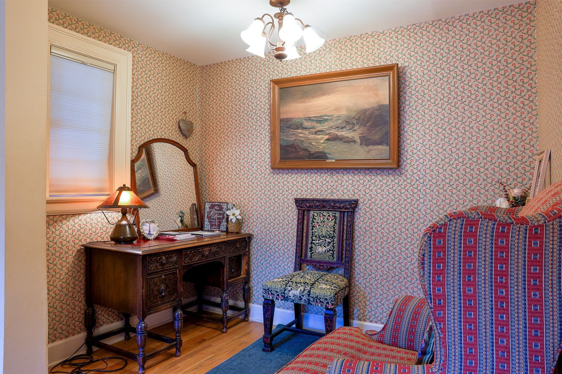 A room with a desk a chair and a painting on the wall