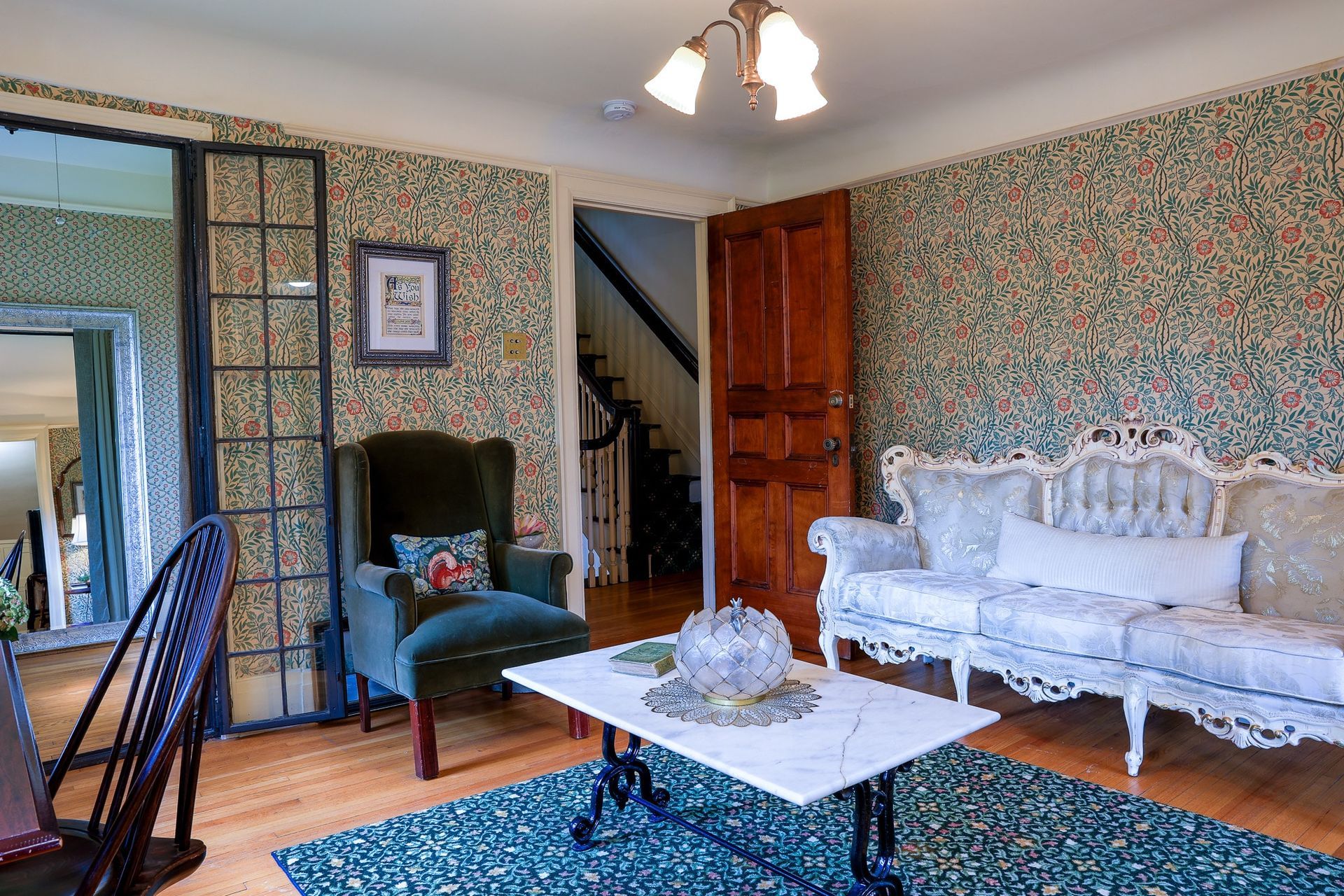 A living room with a couch , chair , coffee table and mirror.