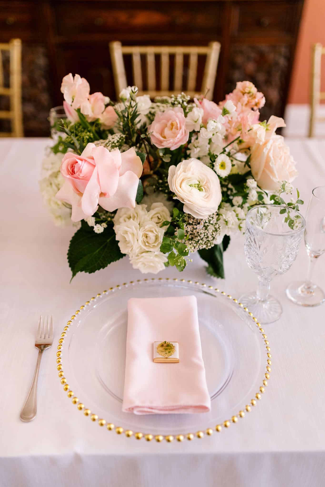 A table set for a wedding reception with a vase of flowers on it.
