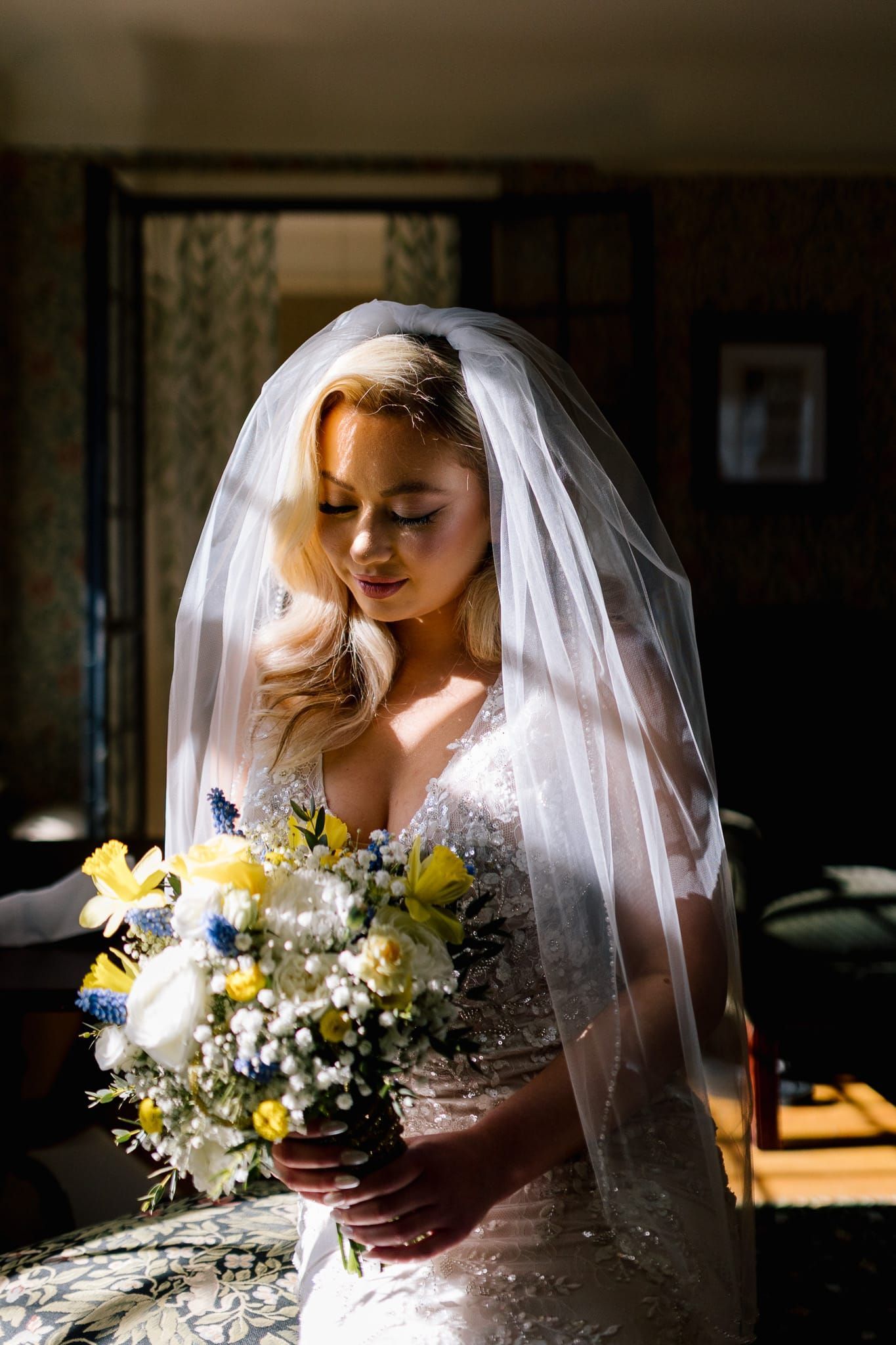 A bride in a wedding dress and veil is holding a bouquet of flowers.