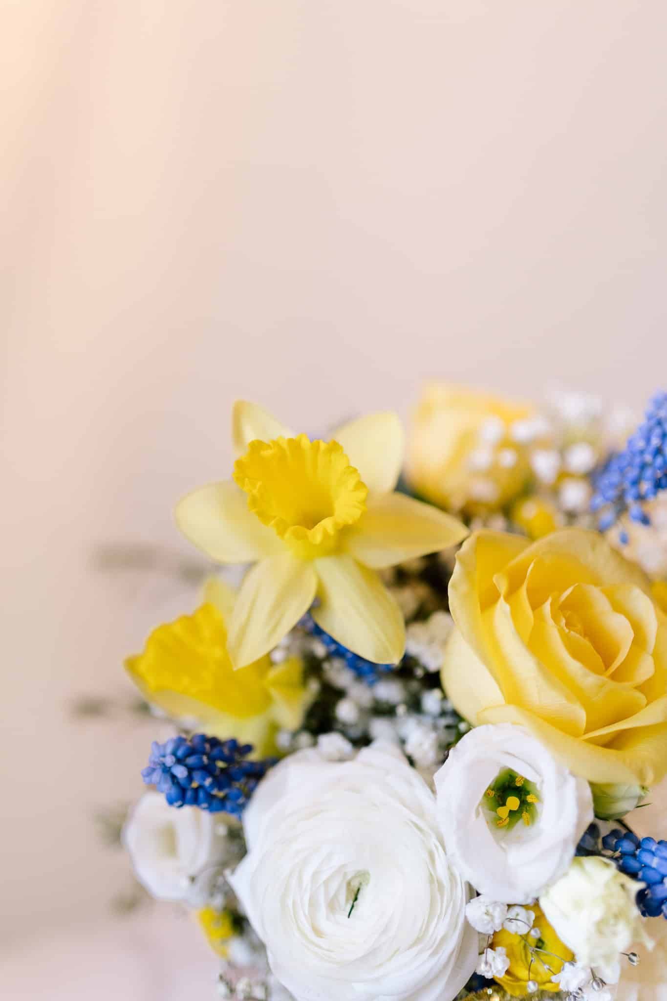 A close up of a bouquet of yellow and blue flowers on a table.