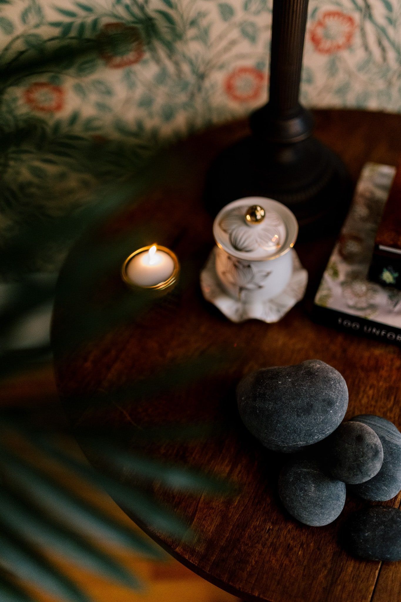 A wooden table with a candle and rocks on it.