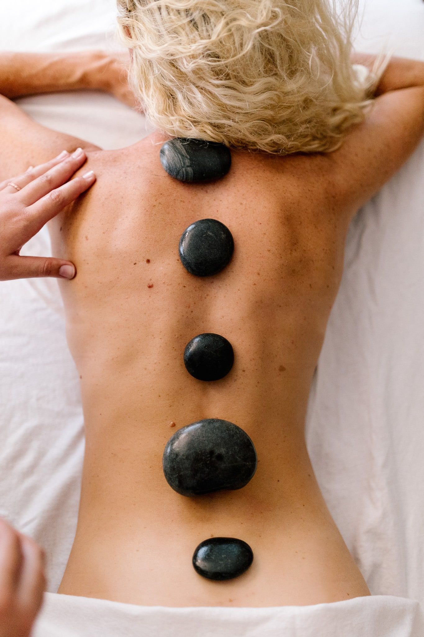 A woman is getting a hot stone massage on her back.