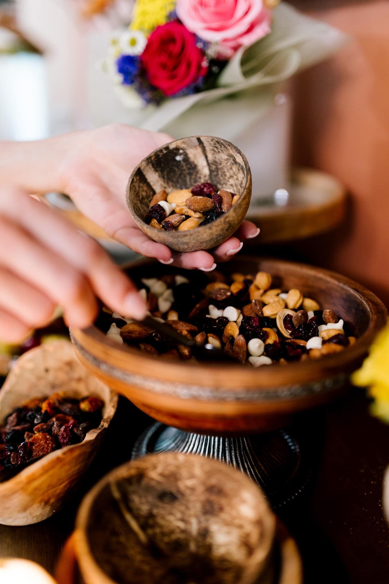 A person is pouring nuts into a bowl on a table.