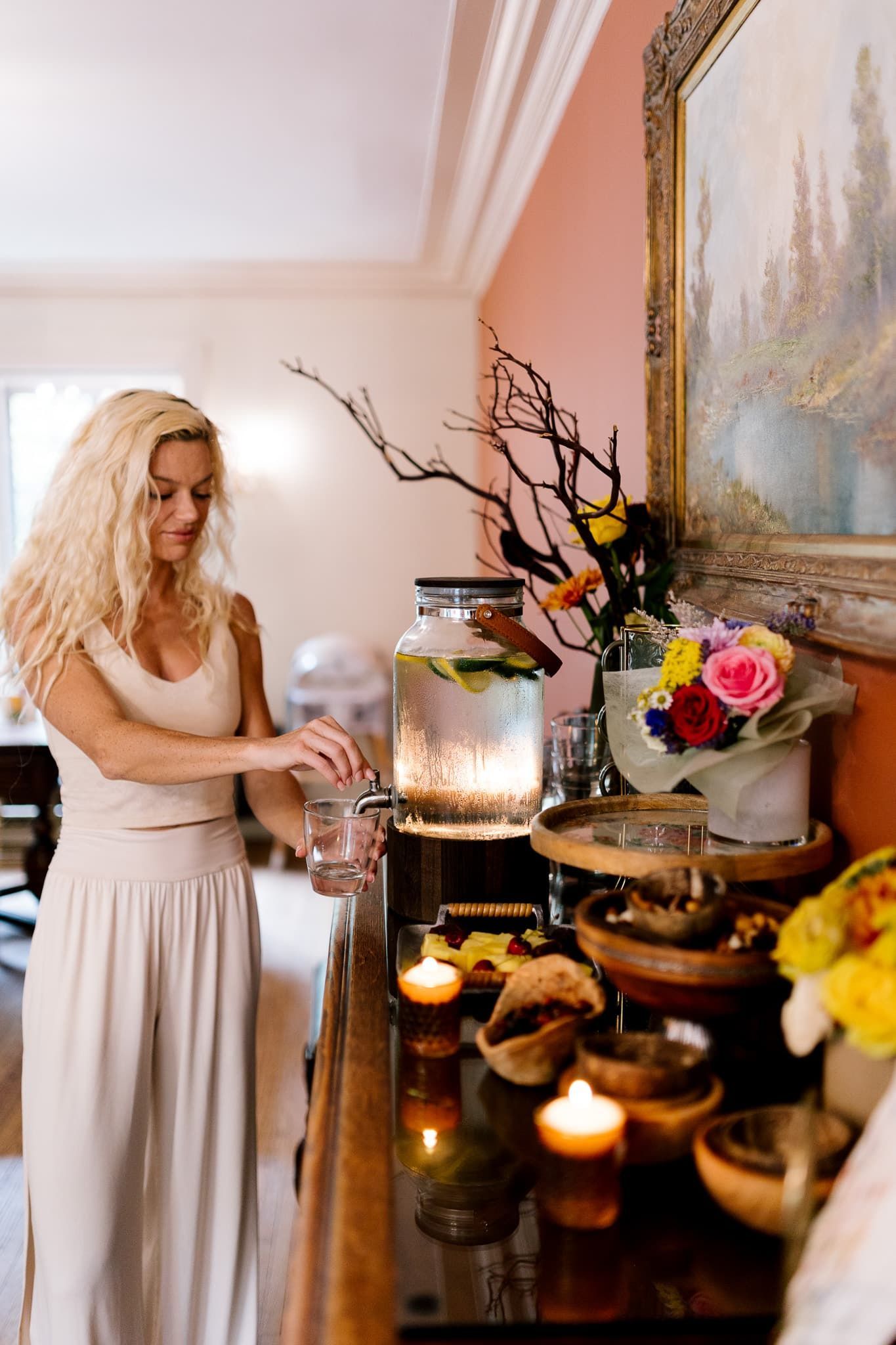 A woman is pouring water into a jar on a table.