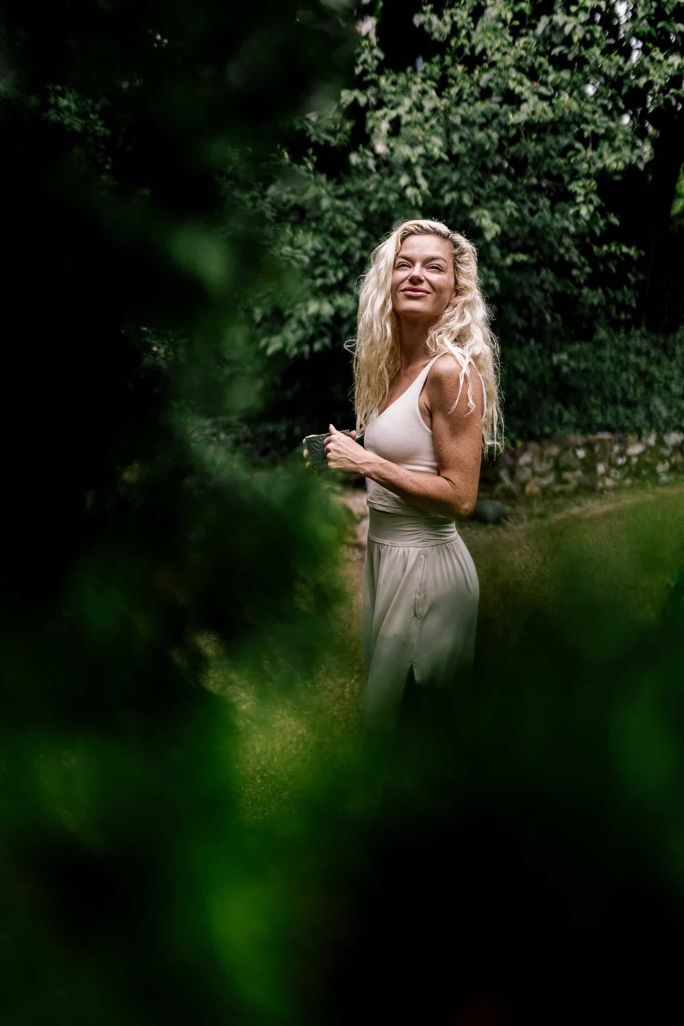 A woman in a white dress is standing in the woods.