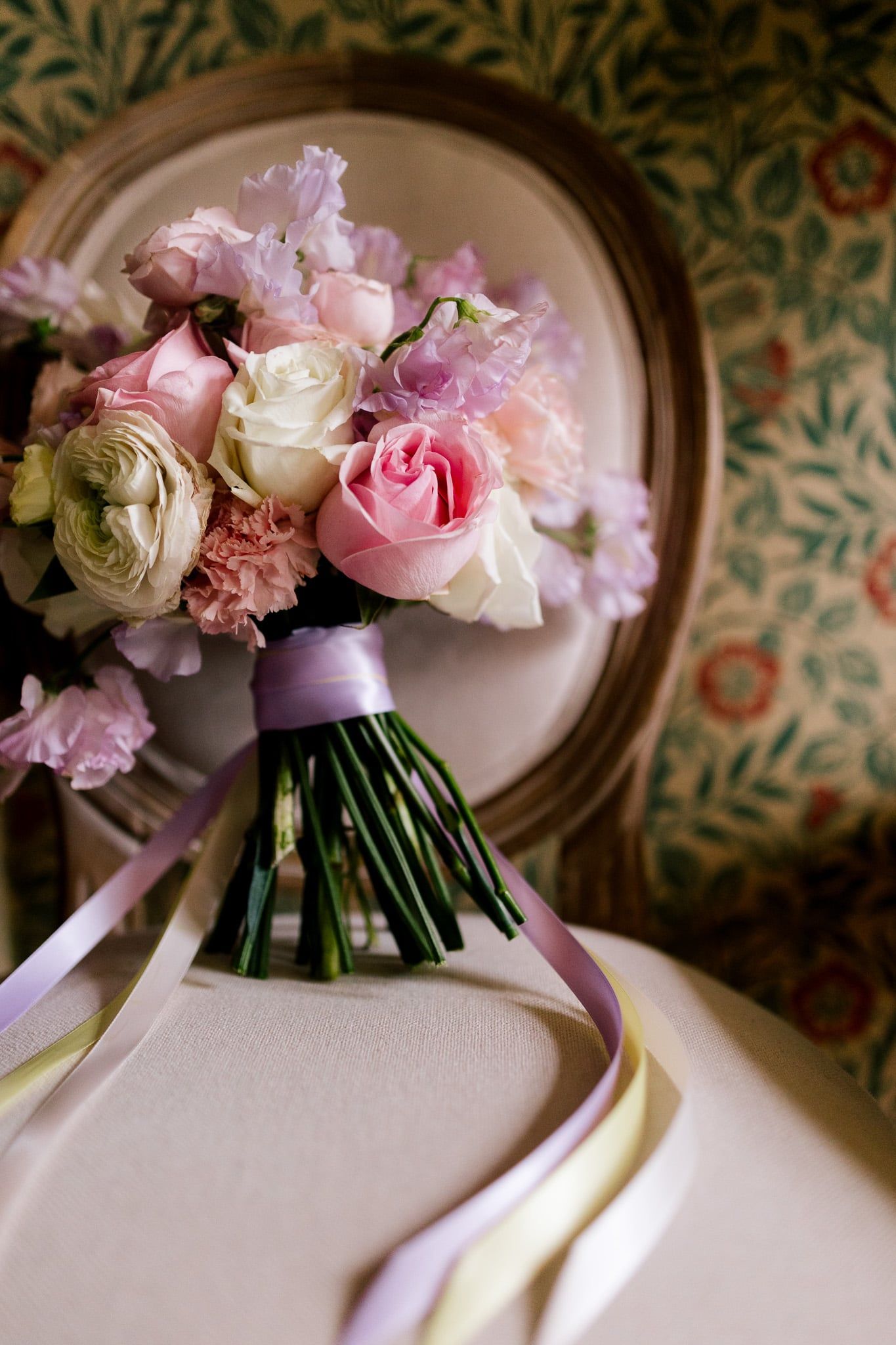 A bouquet of pink and purple flowers is sitting on a chair.