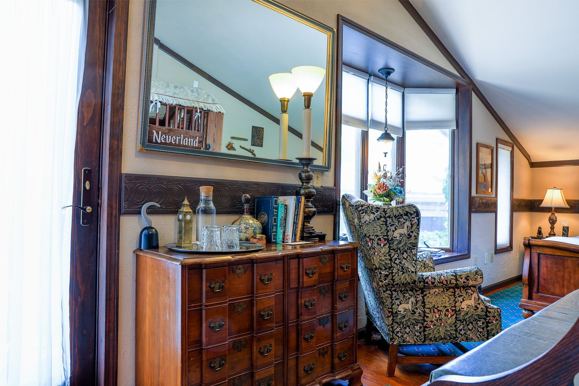 A living room with a dresser , chair , and mirror.