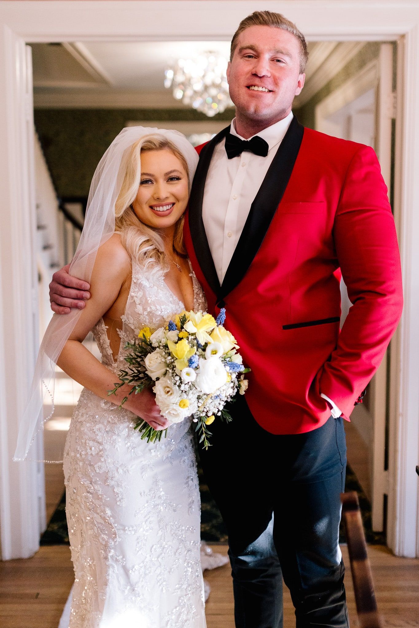 A bride and groom are posing for a picture while the bride is holding a bouquet of flowers.