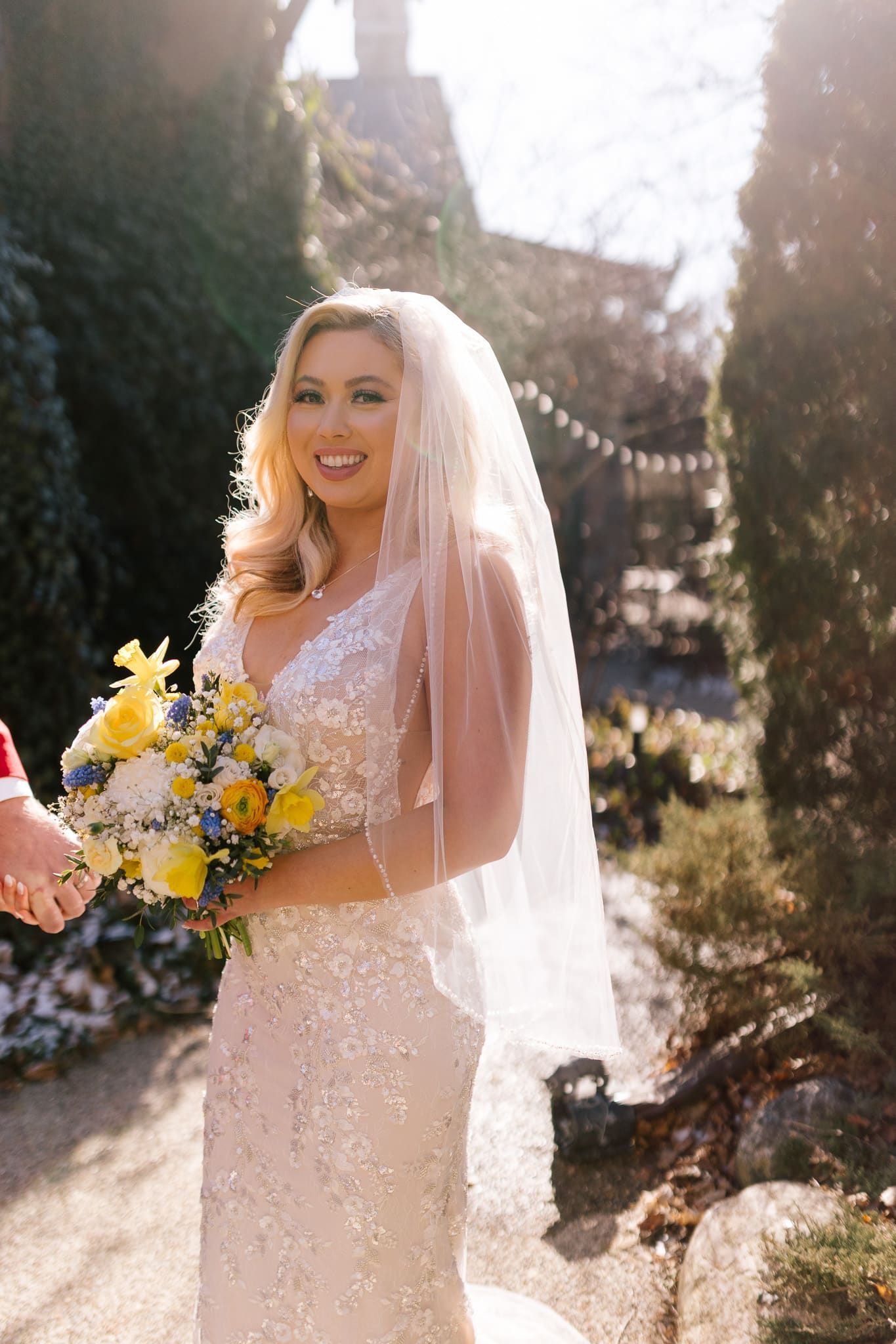 A bride in a wedding dress and veil is holding a bouquet of flowers.