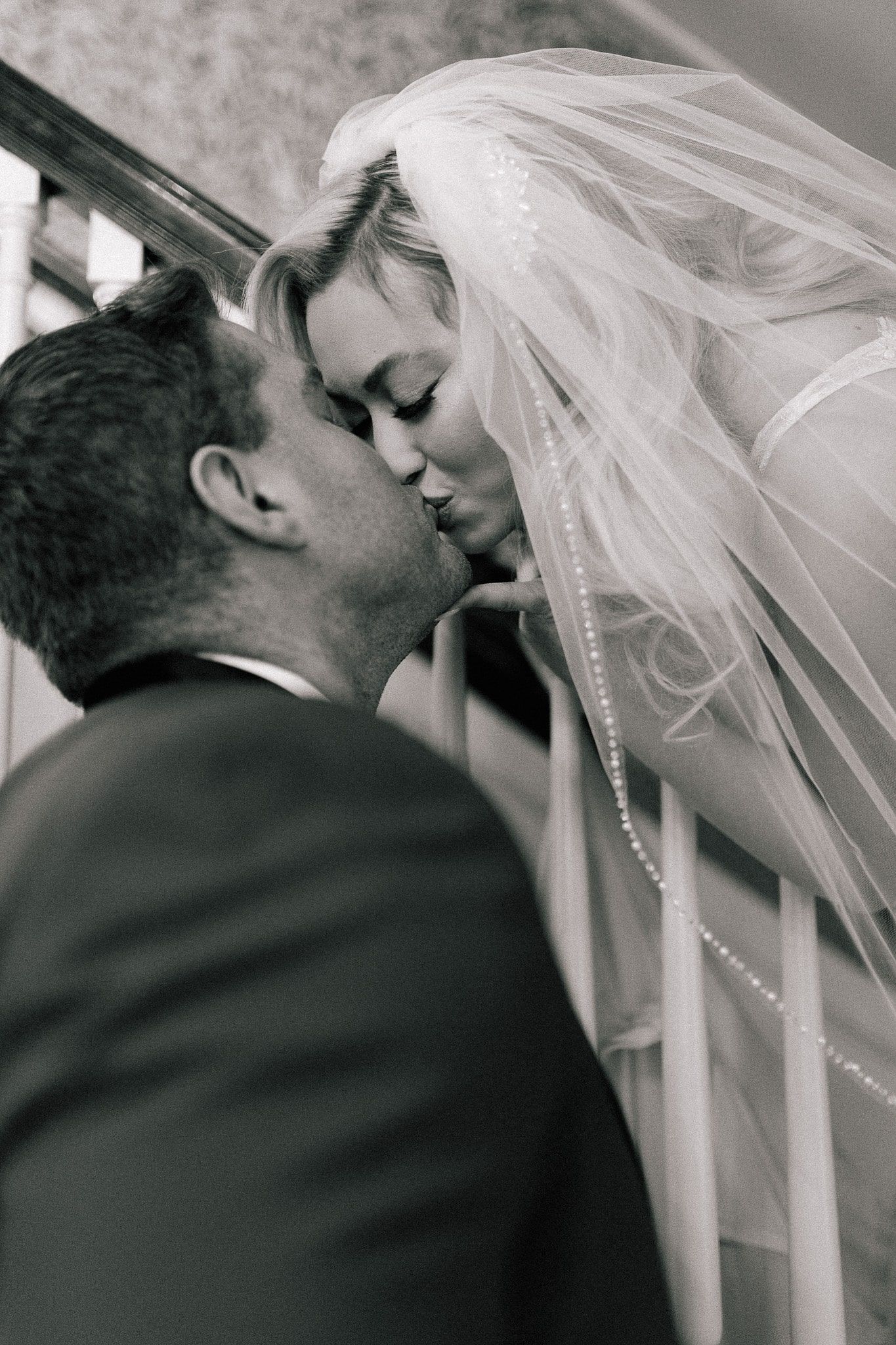 A bride and groom kissing on a set of stairs.