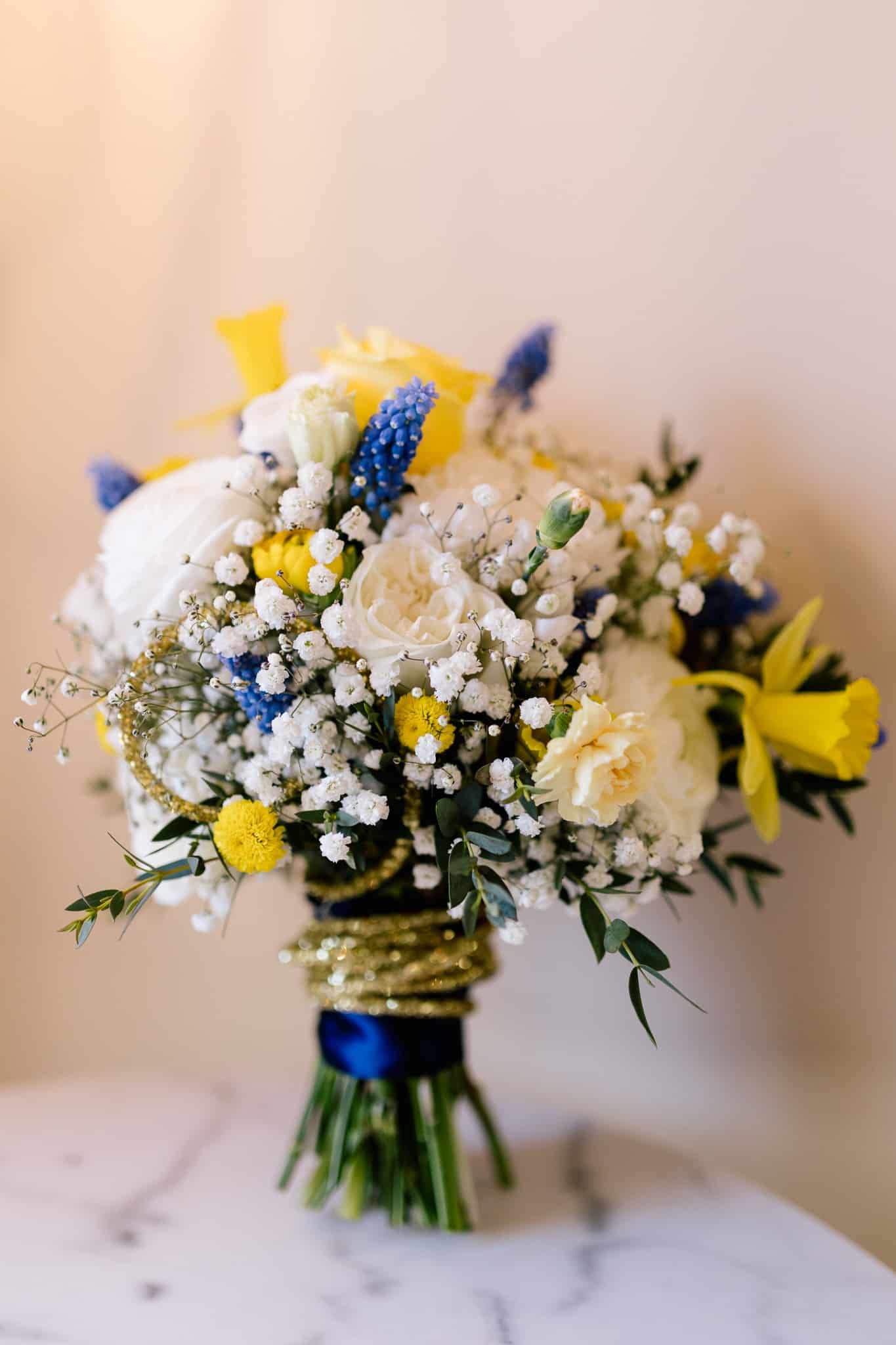 A bouquet of yellow and blue flowers is sitting on a table.