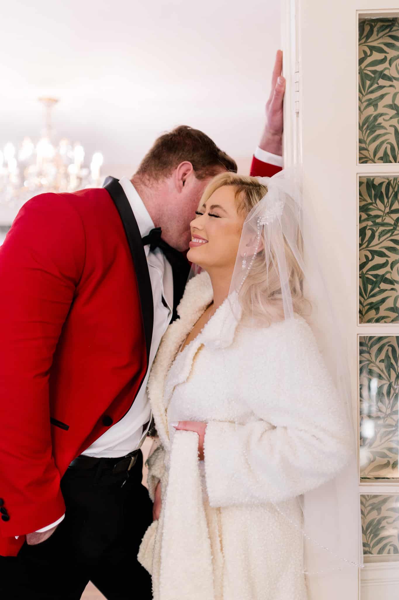 A man in a red suit is kissing a woman on the cheek.