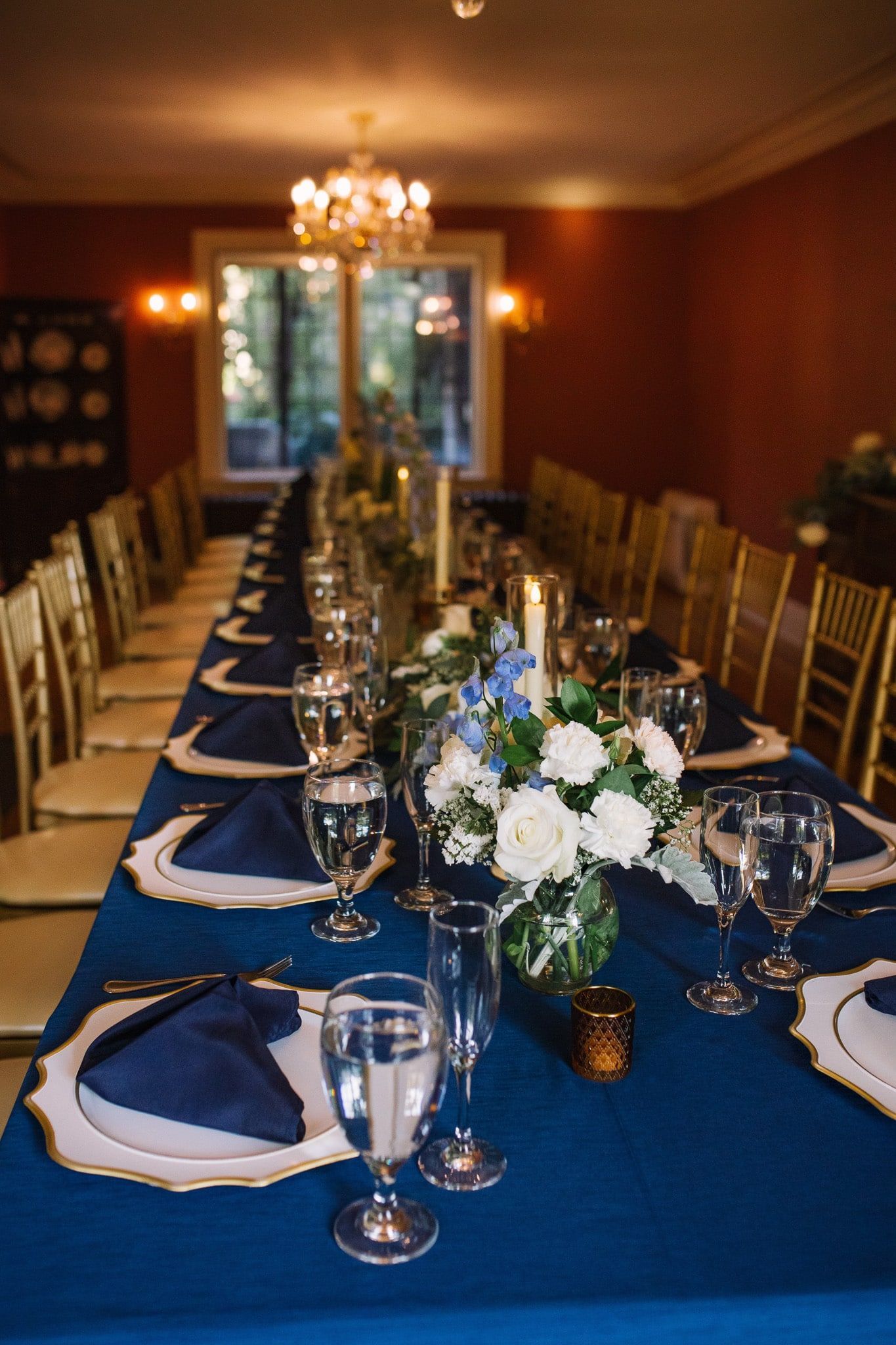 A long table with plates , glasses , and flowers on it.